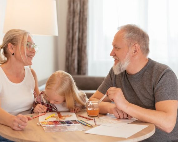 Grandparents and a child bond over painting at a cozy home setting, smiling and focused.