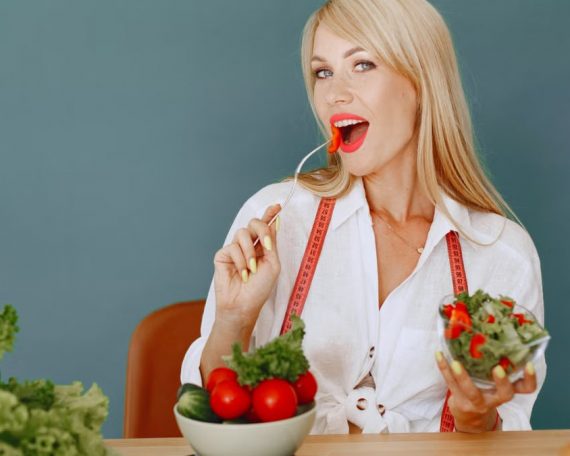 Woman enjoying a fresh salad with tomatoes and greens, promoting healthy eating.