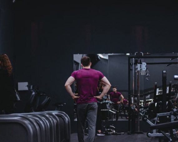 Man in a gym with fitness equipment, highlighting a healthy lifestyle.